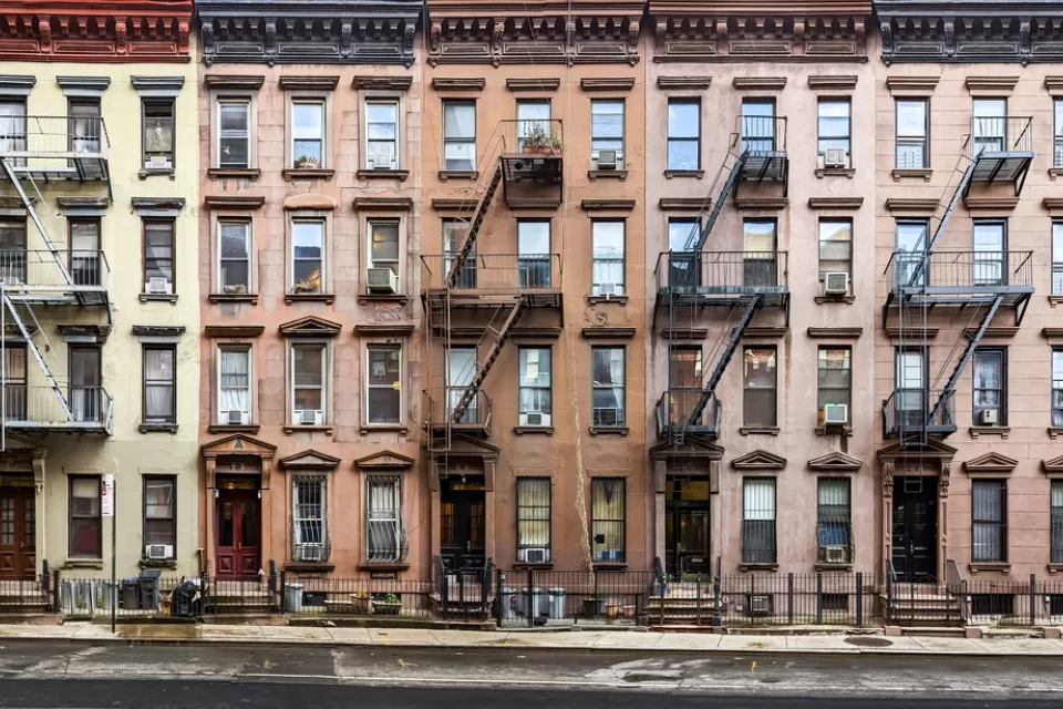 Multicolored four-story brick New York City apartment buildings with fire escapes
